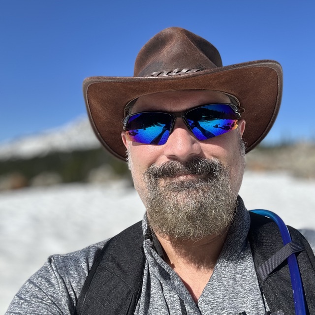 Joe Pantuso in a leather hat and mirrored sunglasses on a snowfield above Big Sky